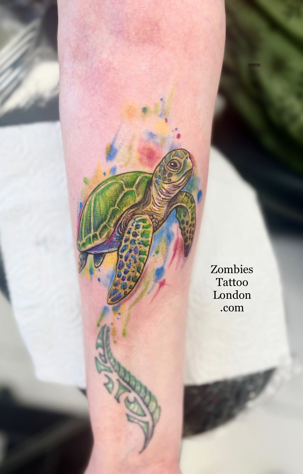 Watercolour-style sea turtle tattoo on a lower leg